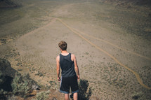 Boy walking on a dirt road.