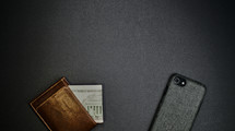 Leather wallet, money next to cell phone.