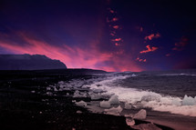 ice along a shore and pink clouds in an indigo sky