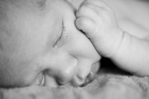 newborn baby sleeping with his hand on his face 