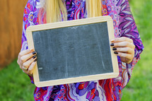 a woman holding a blank chalkboard sign 