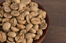A Bowl of Raw Green Coffee Beans on a Wood Background
