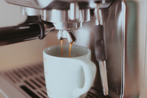 A double espresso shot pouring into a coffee mug.
