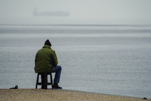 man on a stool along a shore 