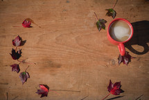 chai and red fall leaves on wood 