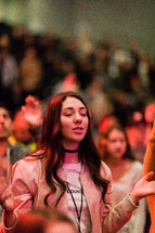 A young woman praying in a church service.