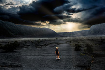 a man standing under cloudy skies in a valley