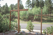 three wooden crosses by the side of a road 