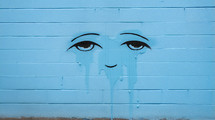 Sad, crying face on a blue wall. 
