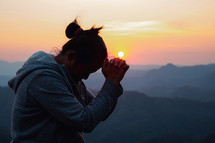 Woman praying at sunset