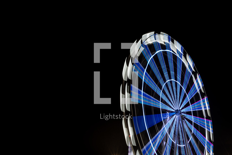 Ferris wheel illuminated at night with long exposure and isolated on black sky