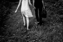 a couple walking through grass holding hands 