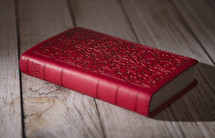 red Bible on a wood floor 
