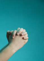 praying hands against a blue background