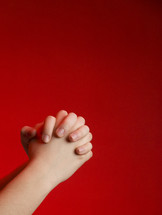 praying hands against a red background 