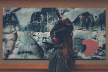 a woman standing in front of artwork on a wall 