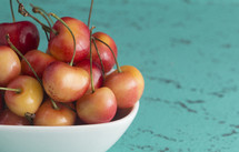 Sweet and Beautiful Red and Yellow Golden Cherries on a teal Background