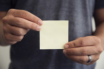 man holding a blank post-it note 