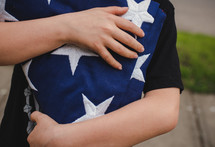 child carrying a folded flag 