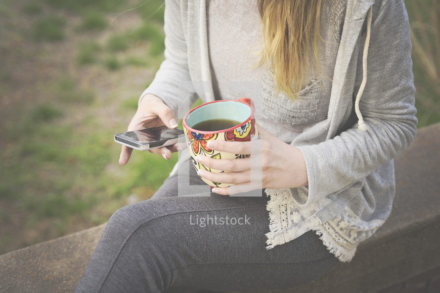 a woman holding a coffee mug and texting 