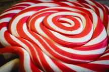 Close up from a Christmas lollypop on a wooden background. Red and white swirl. Background for Christmas.