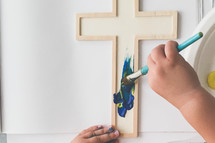 a toddler painting a cross with a stencil 