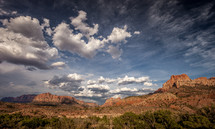 clouds over a red rock mountain 