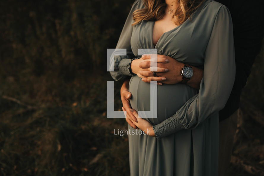 a pregnant woman and her husband hold hands