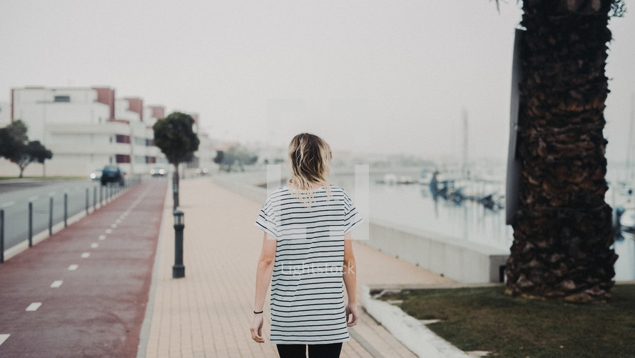 woman walking along a harbor 