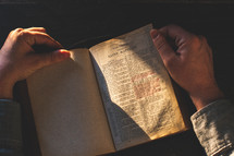 Prayer, man hands over an old open book Holy Bible, wooden desk background.