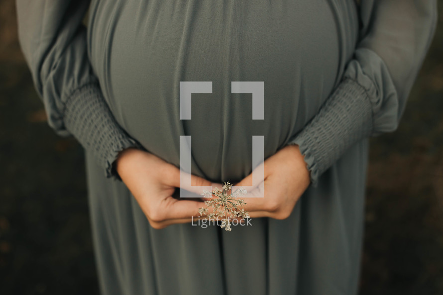 a pregnant women holds a flower in front of her belly