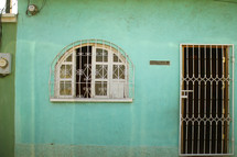 barred doors and window on mint green house 