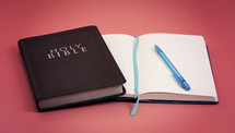A Holy Bible with a Notebook to Study on a Bright Pink Background