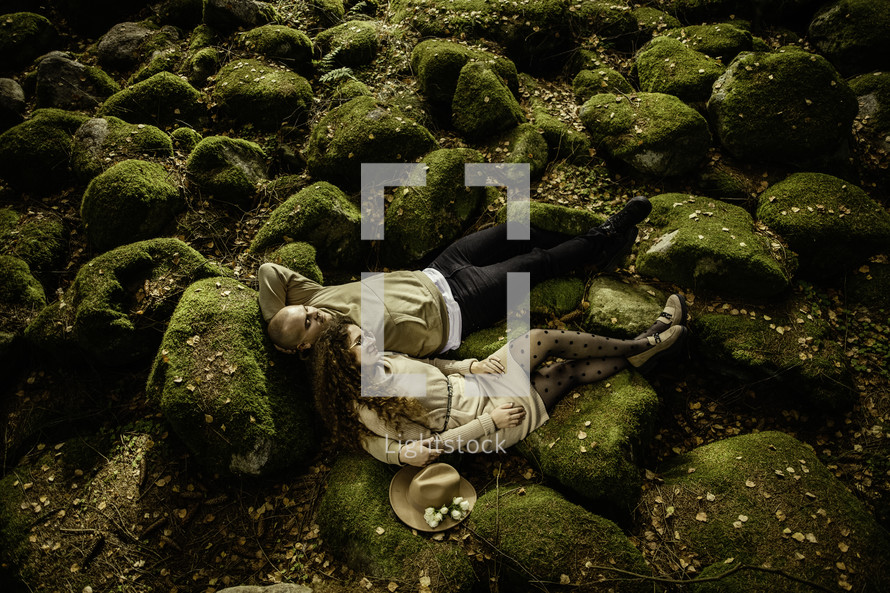 Couple laying on moss covered rocks