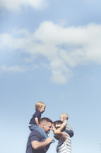children on the shoulders of their mom and dad