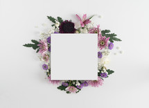 frame of flowers around a white piece of paper 