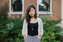 an Asian woman posing with her hands in her pockets outdoors 