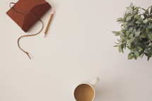 journal, pencil, coffee mug, and house plant on a white background 