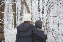 sister and brother standing together outdoors in winter snow 