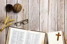 open Bible, notebook, and reading glasses on a wood background  