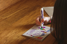 a child coloring a thank you card 