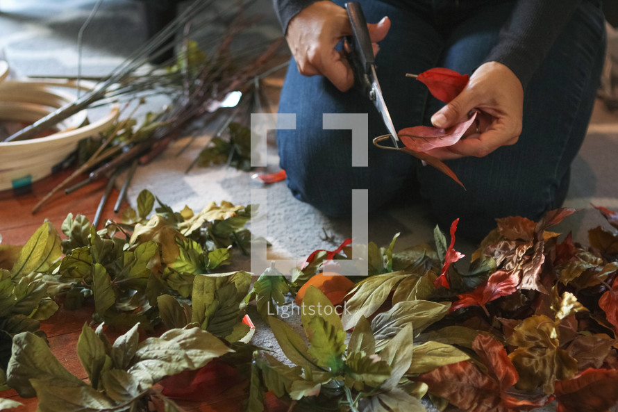 a woman cutting artificial flowers for a fall craft