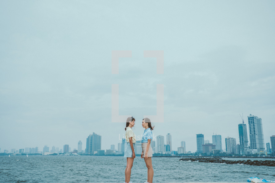 two women standing in front of a city view 