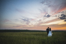 bride and groom walking in a field 