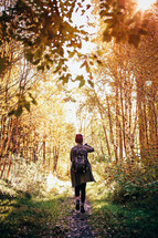 a woman backpacking on a path through a forest 