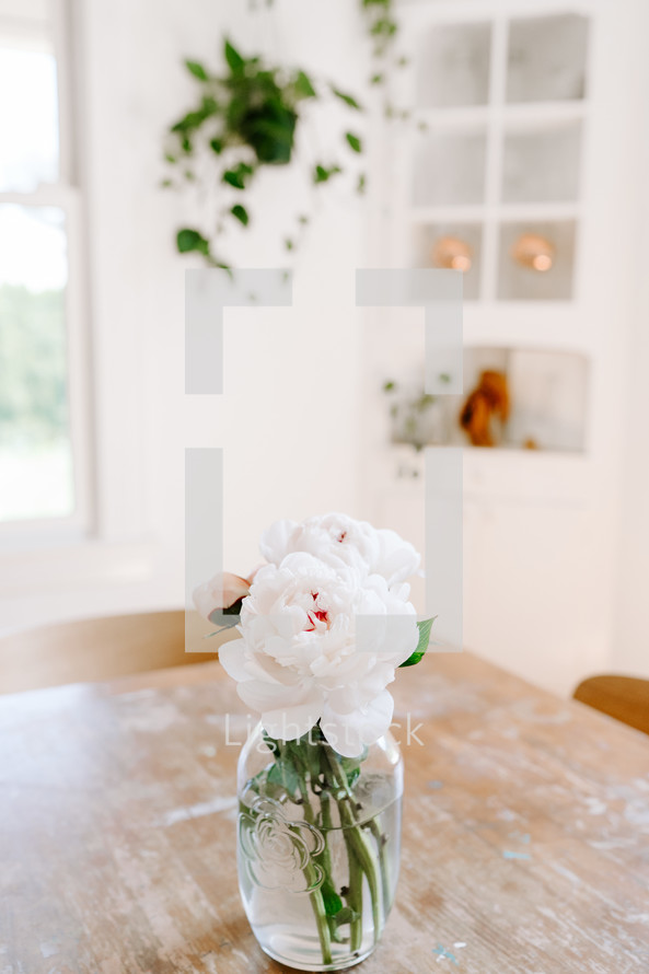 peonies in a vase on a wood table 