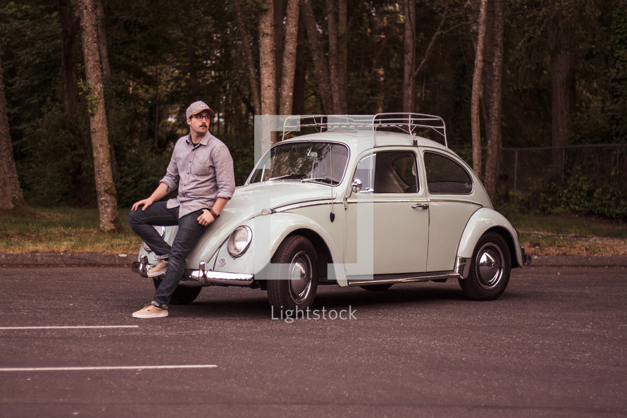 man leaning against a vintage Volkswagen Beetle 
