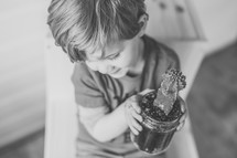 a boy holding a cactus in a mason jar 