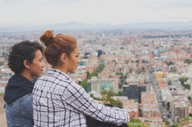 women taking in the view of a city below 