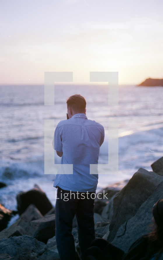 a man taking a picture with a camera while exploring a rocky coastline 